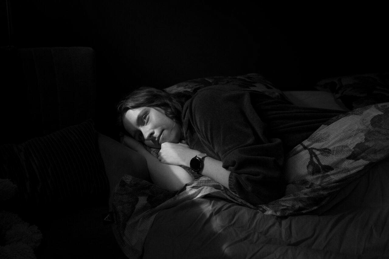     Black and white portrait of Long COVID patient Laure Wiggers lying in bed